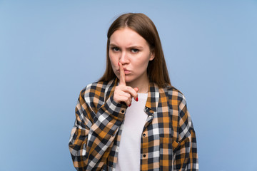 Young woman over blue wall doing silence gesture