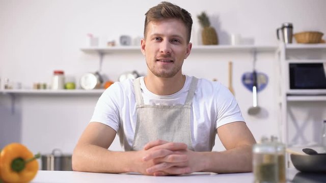 Handsome young chef smiling into camera, ad of culinary courses, nutrition tips