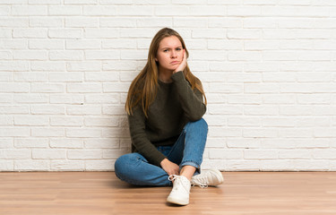 Young woman sitting on the floor thinking