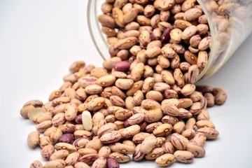 Tarro de judías pintas volcado sobre fondo blanco