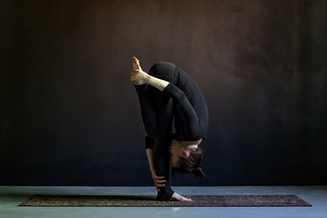 woman practicing yoga, standing forward bend exercise, head to knees, uttanasana