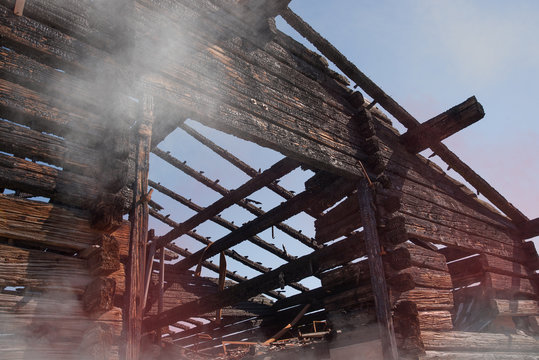 In Rauch geh&uuml;llter, verkohlter und verbrannter Holzbau als Brandruine