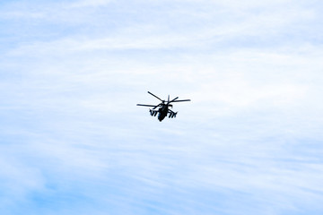 Russian military combat attack helicopter K-52 Alligator flies against a blue sky and clouds