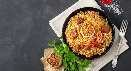 Oriental cuisine. Uzbek pilaf or plov from rice and meat in a cast iron pan. Top view vith copy space.