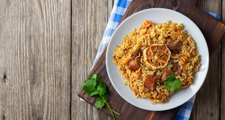 Oriental cuisine. Uzbek pilaf or plov from rice and meat. Wooden rustic background. Top view vith copy space.