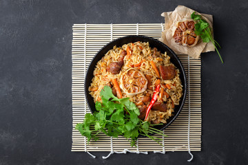 Oriental cuisine. Uzbek pilaf or plov from rice and meat in a cast iron pan. Top view vith copy...