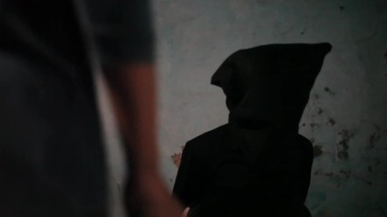 Dolly shot of a man wearing green colored t-shirt and moving towards the other man which is wearing black colored attire with a bag covering his face.