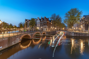 Long exposure boat cruising along the Amsterdam calm canal at the blue sunset hour, Netherlands