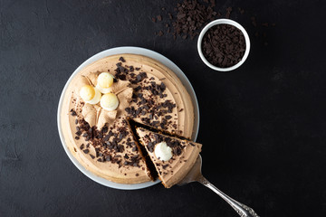 Tasty cake decorated with cream and dark chocolate on black background. Top view with copy space.
