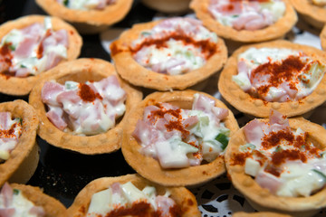Fish and meat salads in tartlets on a plate.