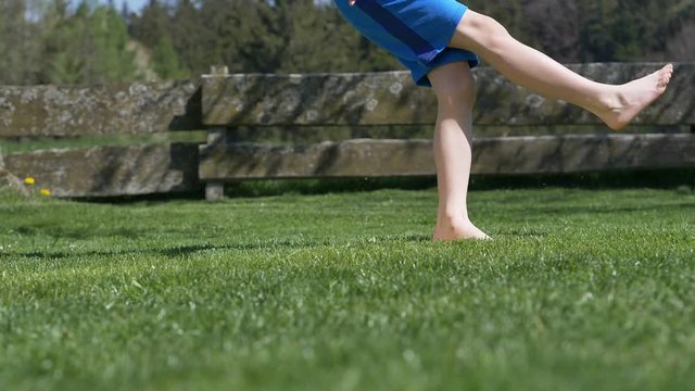 video shows a young boy kicking a soccerball barfoot 