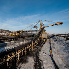 delivery of iron ore by a conveyor belt from a warehouse and loading into railway dump cars.
