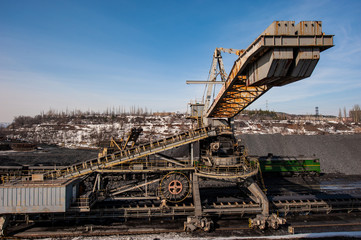 Fototapeta na wymiar delivery of iron ore by a conveyor belt from a warehouse and loading into railway dump cars.
