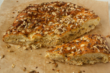A part and piece of pie with meat and cheese filling, grains and seeds on top