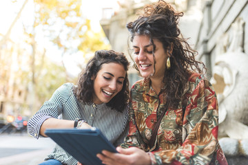 Two Friend Girls Using Cellphone Outdoors.