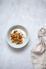 Baked apple with cinnamon and vegan coconut yogurt in rustic plate on marble background with copy space