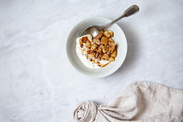 Baked apple with cinnamon and vegan coconut yogurt in rustic plate on marble background with copy space