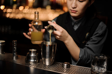 Female bartender pouring cocktail adding sour mix in the shaker