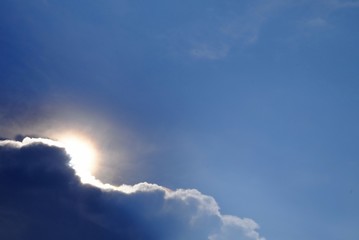Naklejka na ściany i meble Silhouette sun light with fluffy clouds and blue sky