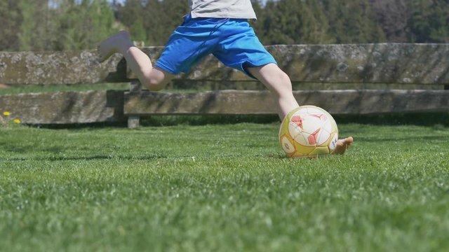 playing soccer in garden - slow motion of young boy kicking a football