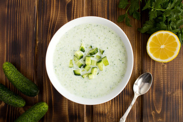 Yogurt smoothies  with  cucumber in the white bowl  on the brown wooden background.Top view.