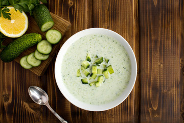 Yogurt smoothies  with  cucumber in the white bowl  on the brown wooden background.Top view.