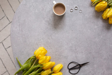 Gray background with yellow flowers tulips and coffee top view