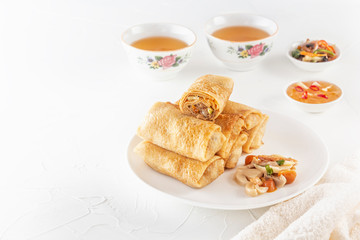 Traditional Chinese tortillas filled - bings in a plate with mushrooms on a white background, cups of tea. Copy space