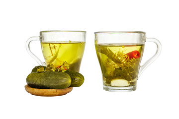 Two glass cups with cucumber pickle and pickled cucumbers in a wooden plate isolated on white background