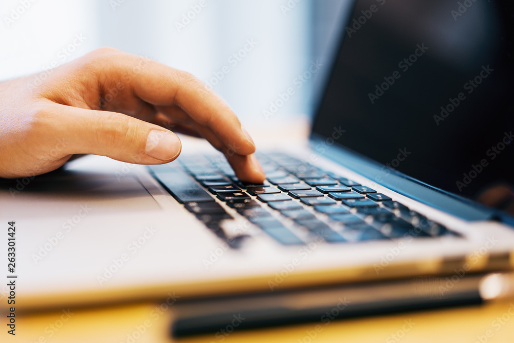 Poster sideview of man using laptop on desktop
