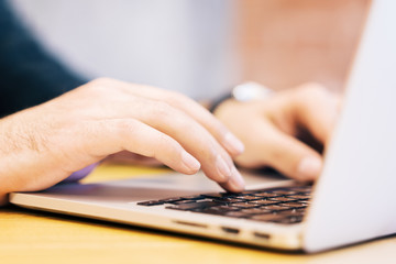 Sideview of male using laptop on desktop