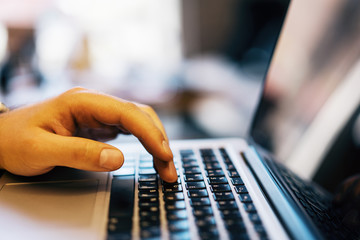 Sideview of male using laptop on desk top