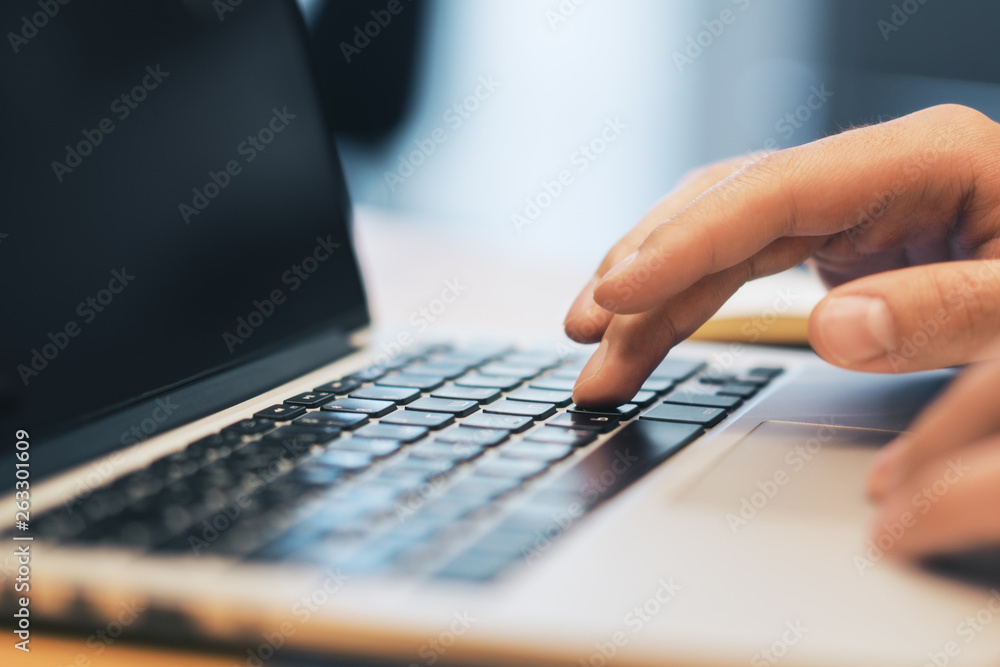Poster sideview of man using laptop on workspace