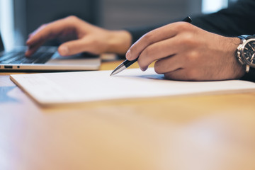 Sideview of businessman doing paperwork with laptop