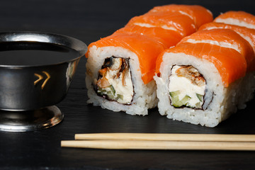 Philadelphia roll sushi with salmon, avocado, cream cheese served on black stone slate