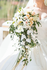 Bride with tender arms holds wedding bouquet 
