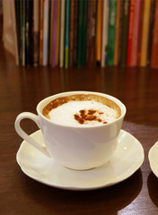 Cup of Cappuccino Coffee with Blurry Row of Books in Background
