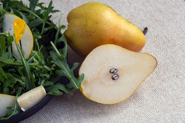 Two big sweet pears near the black plate. Easy tasty summer salad with pear, arugula, brie cheese,...