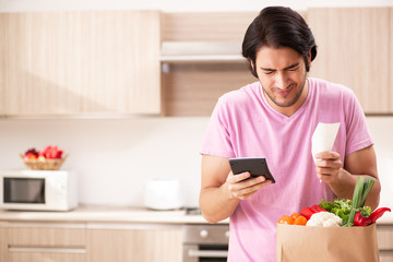 Young handsome man with vegetables in the kitchen 