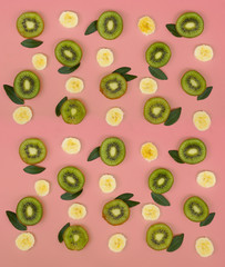 Colorful fruit pattern of fresh kiwi and banana slices on pink background. From top view
