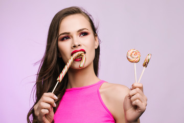 Sexy girl eating lollipop. Beauty Glamour Model woman Licking sweet colorful lollipop candy, close-up. Closeup mouth and tongue. Seductive lips, perfect fashion make-up, pink color lipstick
