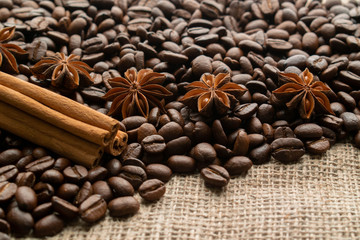 whole bean coffee with star aniseas and cinnamon sticks on light burlap with space for text