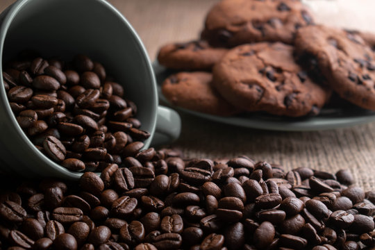 coffee beans crumbled with a cup, in the background a plate of cookies