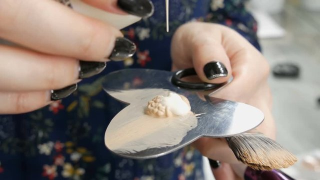 A professional makeup artist uses a make-up concealer. Makeup artist hands stir the foundation