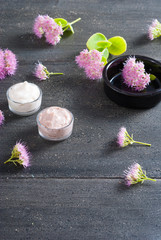 Obraz na płótnie Canvas moisturizer with pink flowers on old black wood table