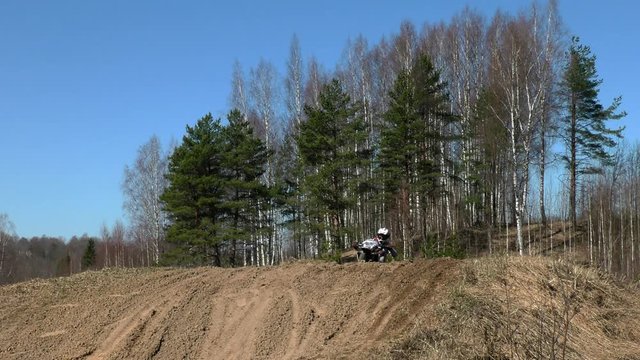 Enduro motorcyclists race over rolling hills. Motorcycle sport in the woodland irregularities.