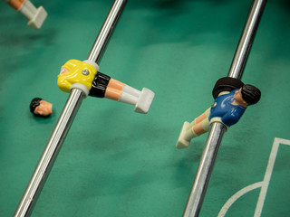 Injured plastic player. Hard game. Table football soccer game with blue and yellow player