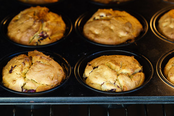 Golden baked vegan vanilla cherry muffins in an oven - close-up