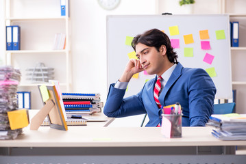 Young male handsome employee in conflicting priorities concept 