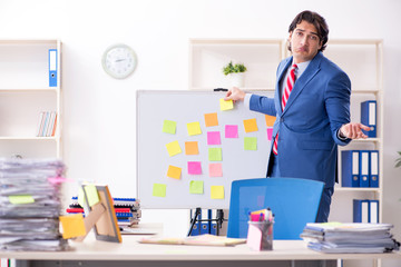 Young male handsome employee in conflicting priorities concept 